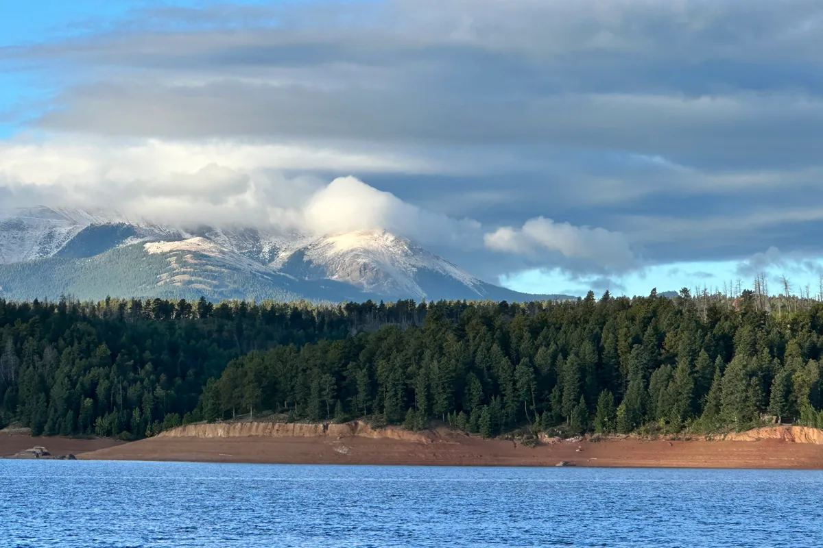 Snow-capped mountains above pine forest at Rampart Reservoir